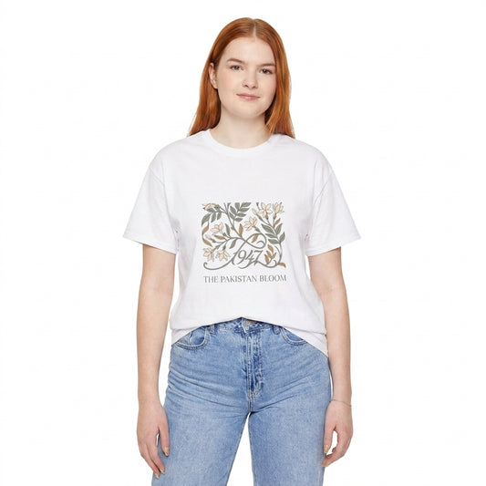 A young woman with red hair wearing a white graphic t-shirt and light blue jeans, standing against a plain white background. The t-shirt features a distressed graphic of a tree with the text '1974' and 'THE PAKISTAN BLOOM l AH Urban Wear Pk