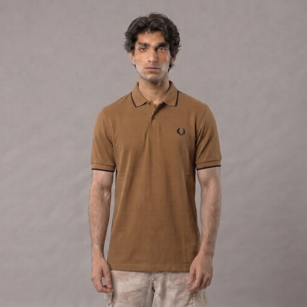 A man wearing a brown short-sleeve polo shirt with black trim and a small embroidered logo on the chest, paired with light beige pants, standing against a neutral gray background | AH Urban Wear PK