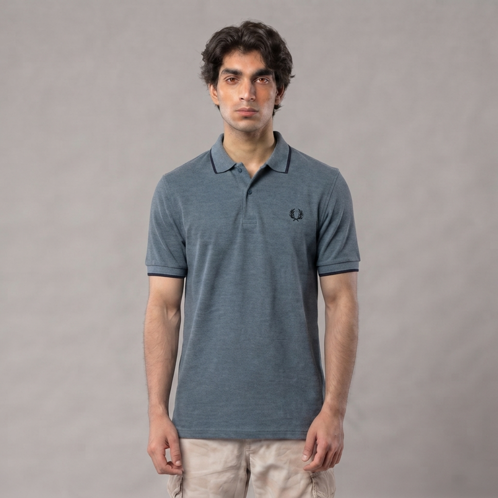 A man wearing a slate gray short-sleeve polo shirt with a small embroidered logo on the chest, paired with light beige pants, standing against a neutral gray studio background | AH Urban Wear PK