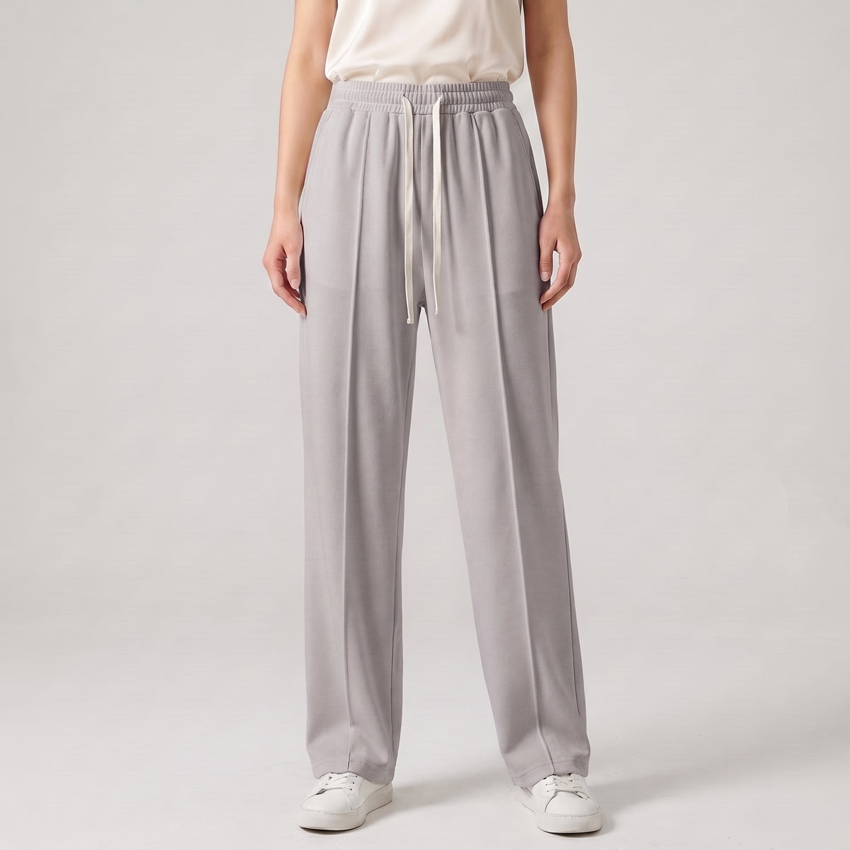 A model wearing light gray wide-leg lounge pants with an elastic waistband and drawstring, paired with a cream top and white sneakers, against a light gray studio background l AH Urban Wear