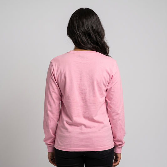 A woman viewed from behind wearing a light pink long-sleeve crewneck shirt and black pants, standing against a plain light gray studio background l AH Urban Wear
