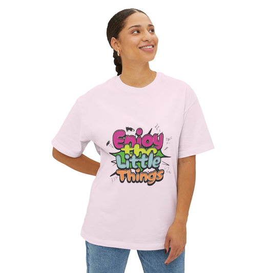 A woman wearing a light pink drop shoulder t-shirt with a colorful graphic that reads 'Enjoy My Little Things' in a graffiti-style font, paired with blue jeans, against a plain white background | AH Urban Wear PK