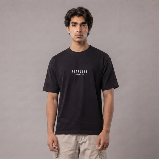 A man wearing a black short-sleeve t-shirt with 'FEARLESS' and 'ARMAGEDDON' printed in white on the chest, paired with light beige cargo pants, standing against a neutral gray studio background | AH Urban Wear PK