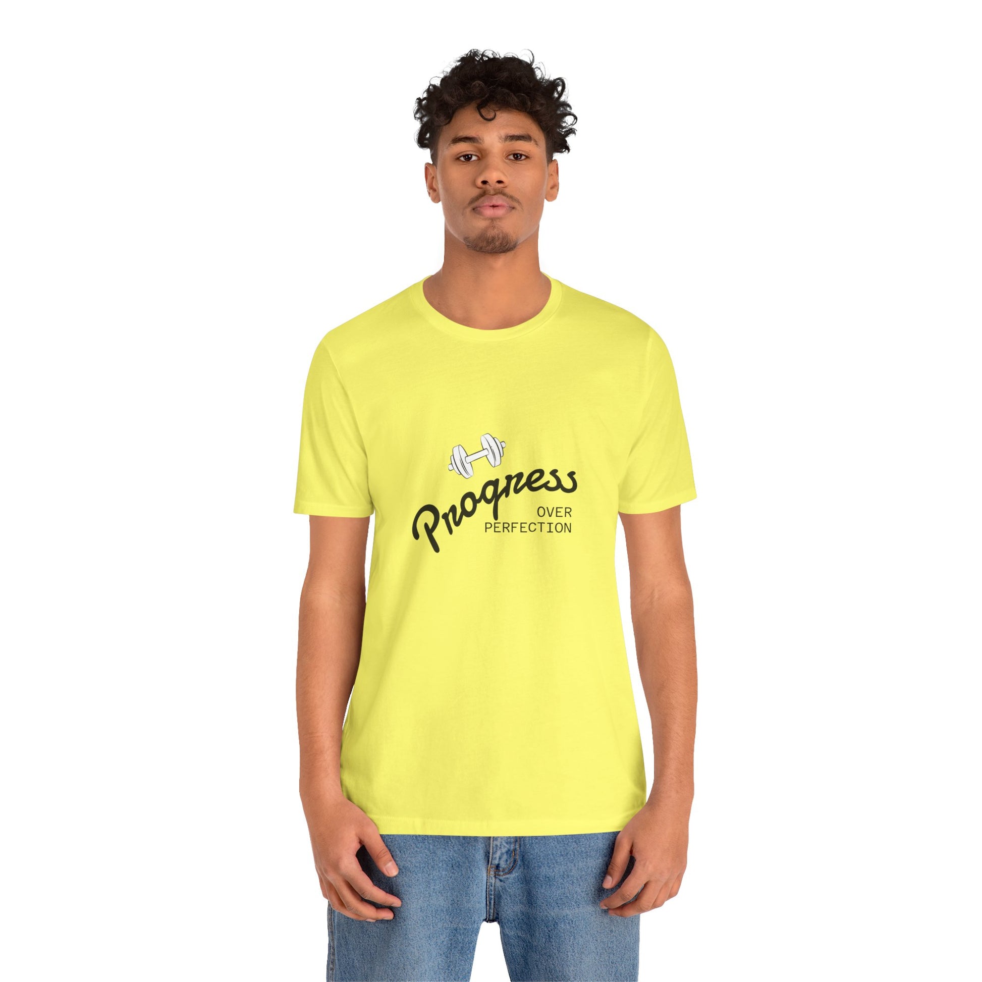 A man wearing a bright yellow t-shirt with a black and white graphic that reads 'Progress OVER PERFECTION' with a dumbbell illustration, paired with blue jeans, against a plain white background | AH Urban Wear PK