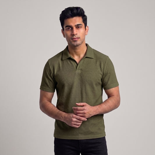 A man wearing a short-sleeve olive green waffle knit polo shirt, standing against a neutral light gray studio background l AH Urban Wear