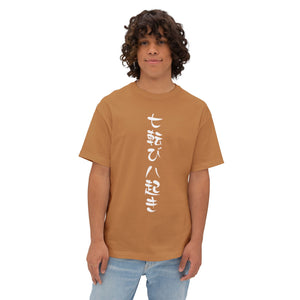A men with curly brown hair wearing a tan drop shoulder t-shirt with vertical white Japanese characters, paired with light blue jeans, against a plain white background. | AH Urban Wear PK