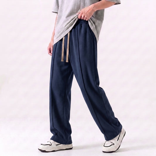 A person wearing loose navy drawstring baggy trouser with a light gray t-shirt and white sneakers, shown from the waist down against a plain light background. l AH Urban Wear Pk