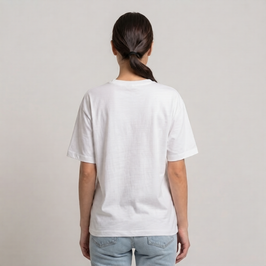 A woman viewed from behind wearing a plain white drop shoulder t-shirt and light blue jeans, standing against a neutral light gray studio background | AH Urban Wear PK