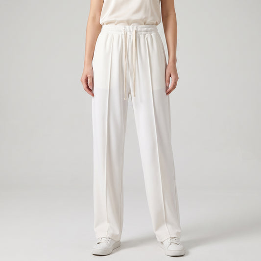 A model from the waist down wearing white baggy trouser with a drawstring waist, paired with white sneakers on a light gray studio background l AH Urban Wear