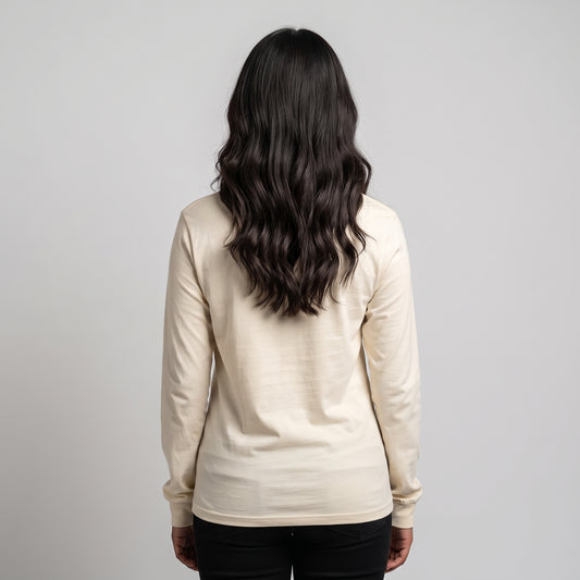 A woman viewed from behind wearing a cream-colored long-sleeve knit top and black pants, standing against a solid light gray background l AH Urban Wear