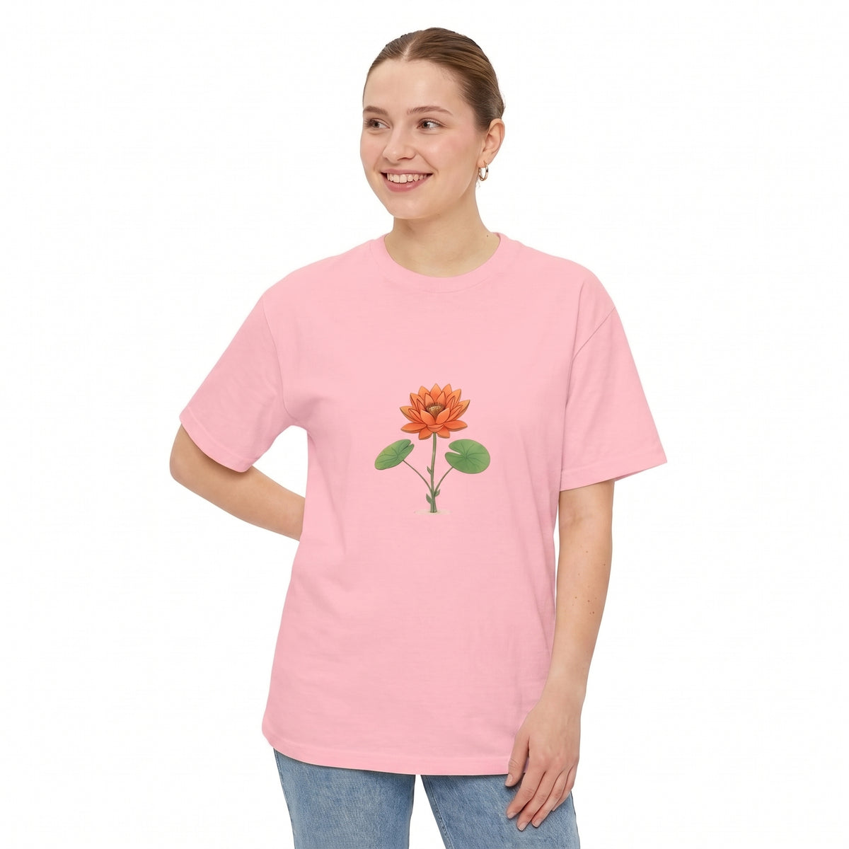 A woman modeling a light pink crewneck drop shoulder t-shirt with a central graphic of an orange lotus flower and green leaves, set against a plain white background l AH Urban Wear