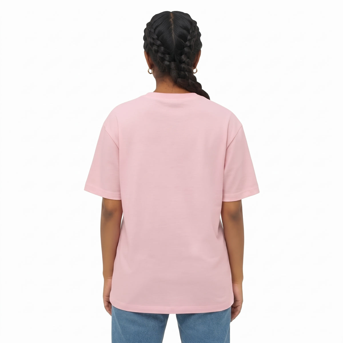 A woman with dark braided hair is shown from the back wearing a light pink drop shoulder t-shirt and light blue jeans against a plain white background.