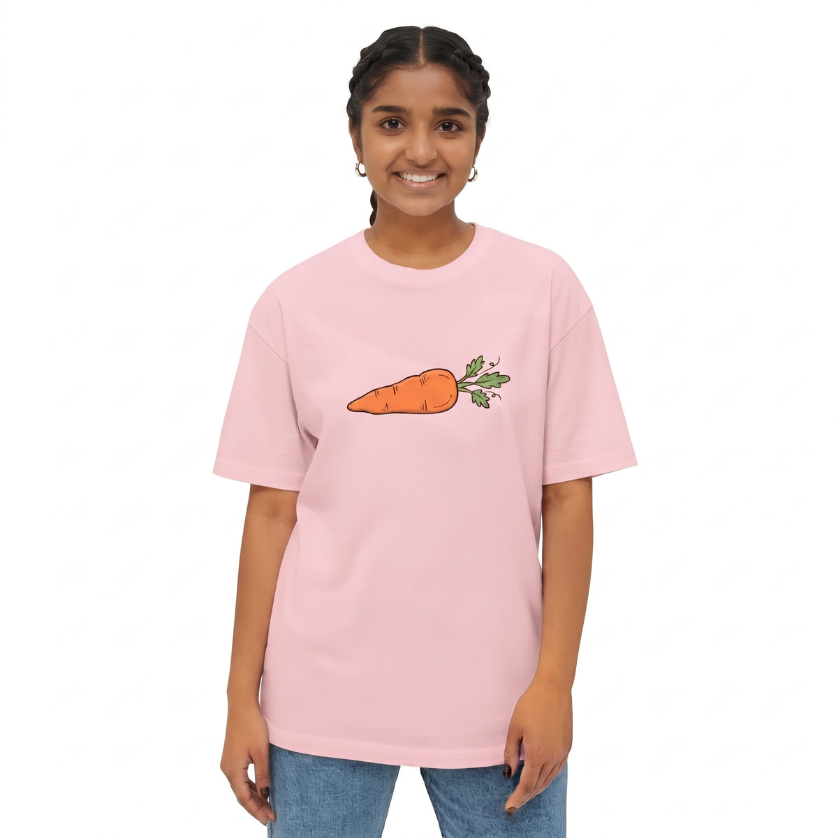 A young girl with braided hair is wearing a light pink drop shoulder t-shirt with a cartoon carrot graphic on the chest, paired with blue jeans, set against a plain white background l AH Urban Wear
