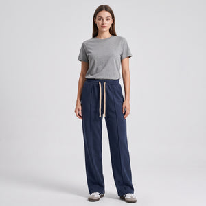 A woman modeling a gray short-sleeve crewneck t-shirt and navy blue baggy trouser against a light gray studio background l AH Urban Wear