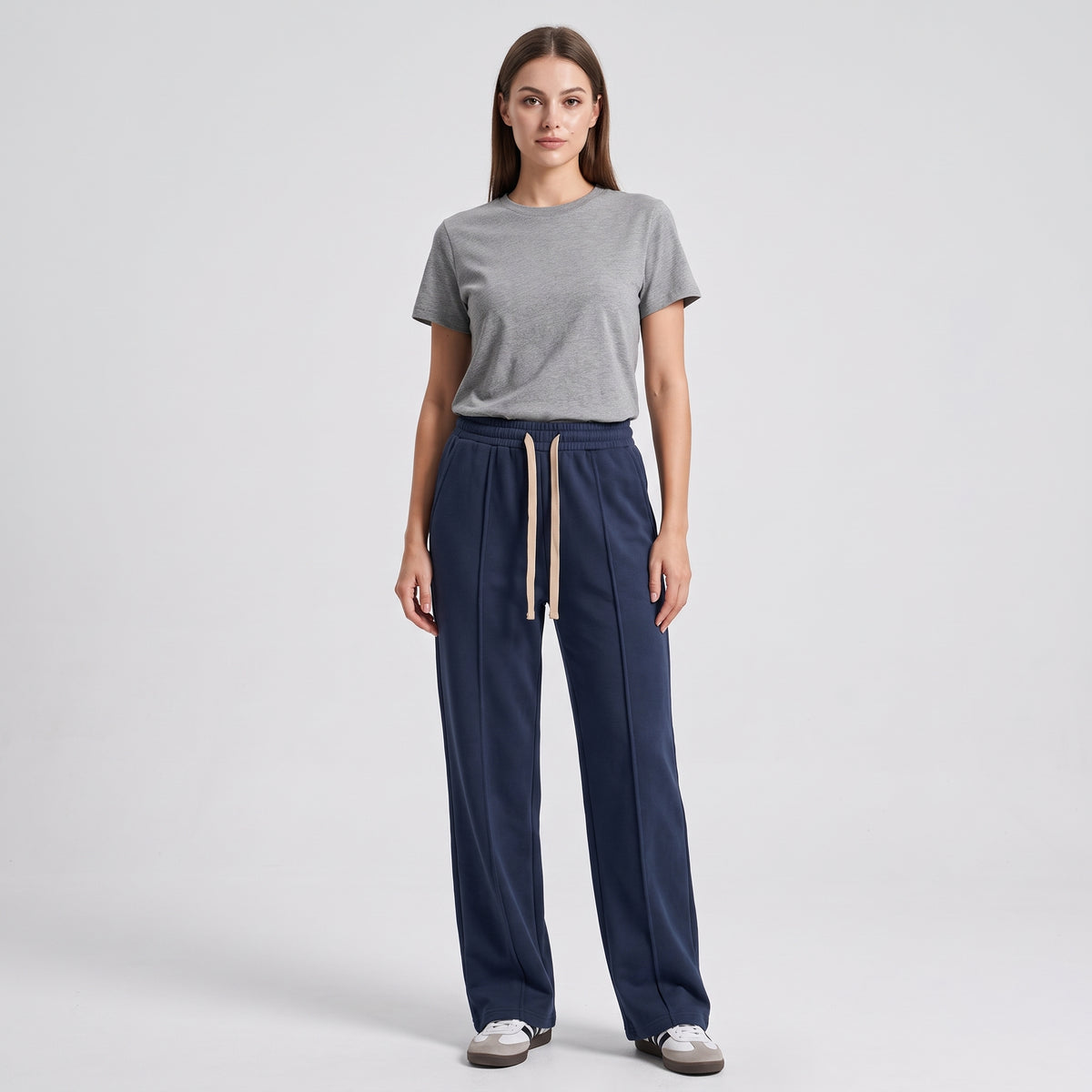 A woman modeling a gray short-sleeve crewneck t-shirt and navy blue baggy trouser against a light gray studio background l AH Urban Wear
