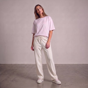 A woman modeling a light pink short-sleeve crewneck t-shirt and off-white drawstring baggy trouser against a neutral studio backdrop l AH Urban Wear Pk